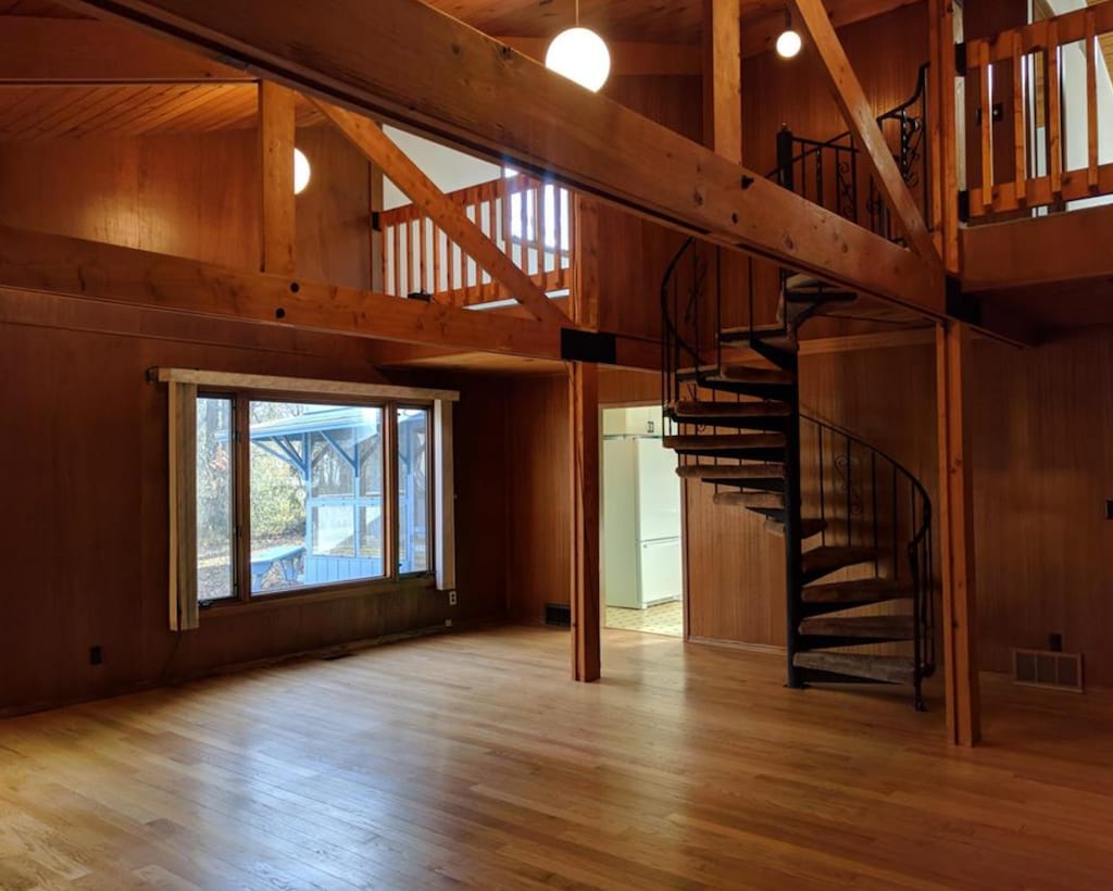 600 Russell St NW, Willmar, MN 56201 - unfurnished living room featuring high vaulted ceiling, stairs, wooden walls, wood finished floors, and a wooden ceiling with exposed beams