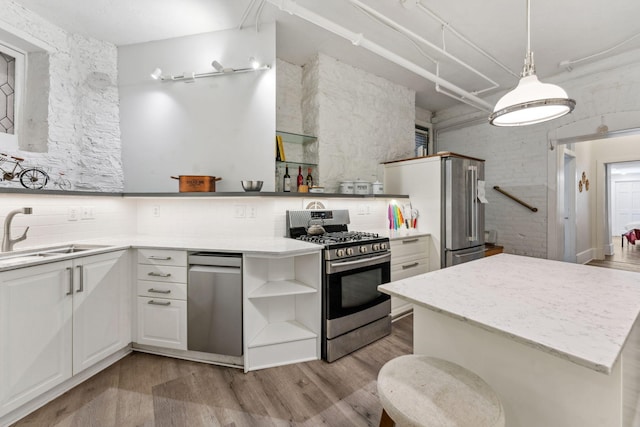 kitchen with open shelves, a sink, wood finished floors, and stainless steel appliances