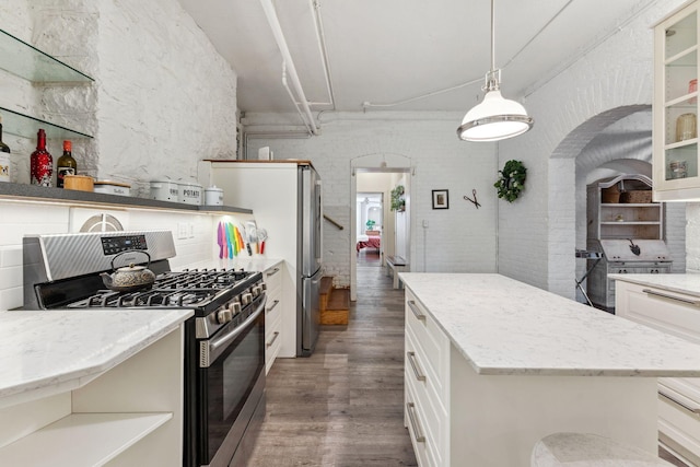 kitchen with open shelves, glass insert cabinets, stainless steel gas range oven, dark wood-type flooring, and white cabinets