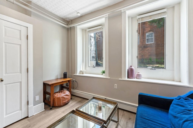 sitting room featuring baseboards, baseboard heating, and wood finished floors