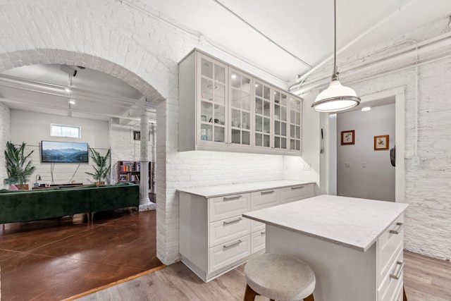kitchen featuring decorative columns, light wood finished floors, white cabinets, and glass insert cabinets