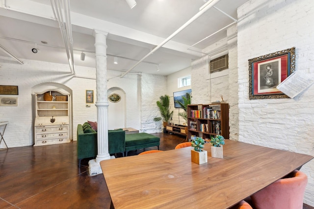 dining area with an AC wall unit, concrete flooring, and ornate columns