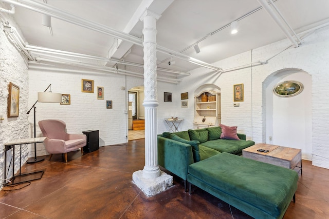 living room featuring finished concrete flooring, arched walkways, and decorative columns