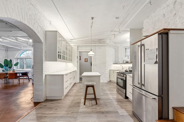 kitchen with appliances with stainless steel finishes, light countertops, a kitchen breakfast bar, a kitchen island, and pendant lighting