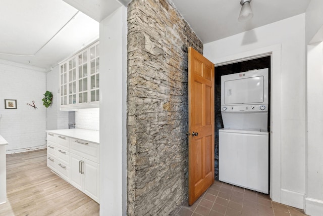 laundry area featuring laundry area, light tile patterned floors, and stacked washer / dryer