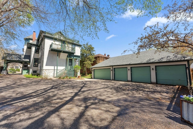 view of side of property featuring an outbuilding, stucco siding, a balcony, and a chimney