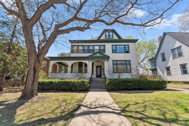 view of front of home featuring a porch, stucco siding, and a front yard