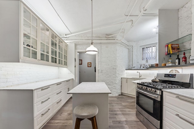 710 Summit Ave Unit 4, Saint Paul, MN 55105 - kitchen with stainless steel gas range, glass insert cabinets, wood finished floors, a center island, and white cabinetry