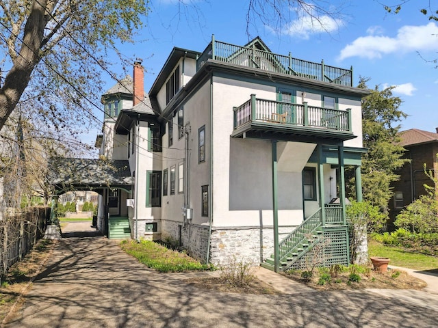 710 Summit Ave Unit 4, Saint Paul, MN 55105 - view of side of property with a balcony, stucco siding, stairs, stone siding, and a chimney