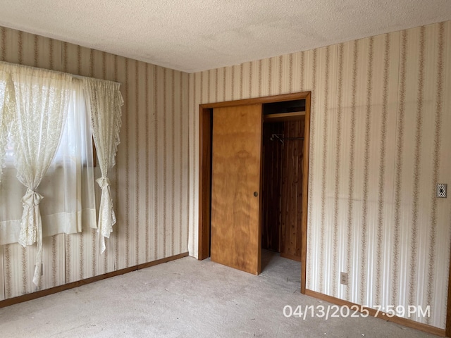 unfurnished bedroom with carpet flooring, a textured ceiling, wallpapered walls, and a closet
