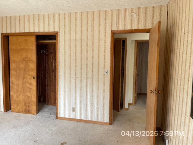 unfurnished bedroom featuring a closet, carpet flooring, wallpapered walls, and a textured ceiling