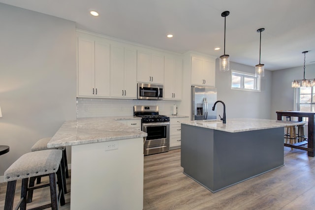 kitchen featuring decorative backsplash, light wood-style flooring, appliances with stainless steel finishes, and white cabinets