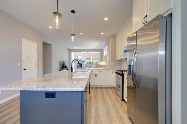 kitchen with a kitchen island with sink, stainless steel appliances, a sink, and light wood finished floors