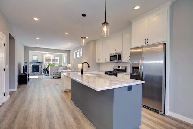 kitchen with a sink, light wood-style flooring, white cabinets, and stainless steel appliances