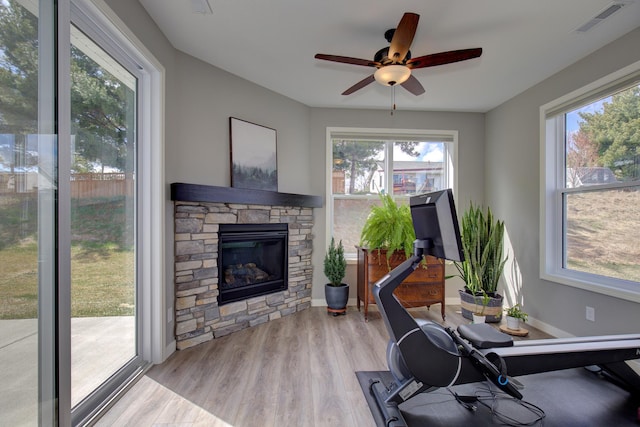 workout area with a ceiling fan, visible vents, wood finished floors, and a fireplace