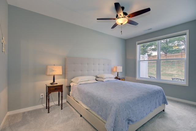 bedroom featuring visible vents, baseboards, ceiling fan, and light carpet