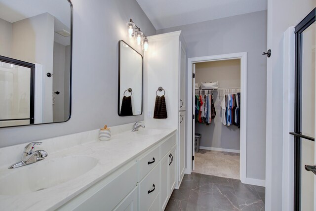 bathroom featuring baseboards, a spacious closet, a sink, and marble finish floor