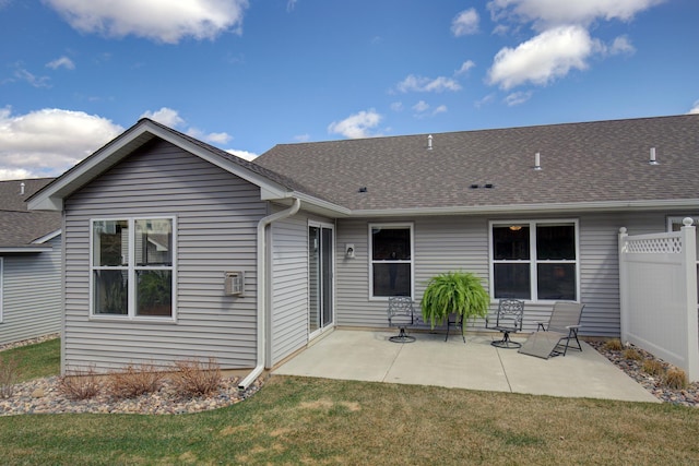 rear view of property featuring fence, a shingled roof, a yard, and a patio area