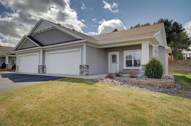 view of front of home with a garage, covered porch, stone siding, a front yard, and driveway