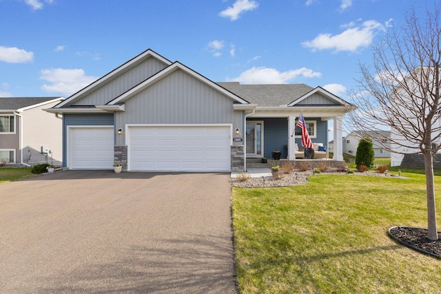 view of front of property with aphalt driveway, a garage, board and batten siding, a front yard, and covered porch