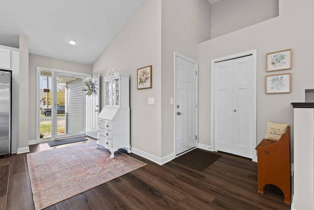 foyer entrance with dark wood-type flooring, baseboards, and high vaulted ceiling