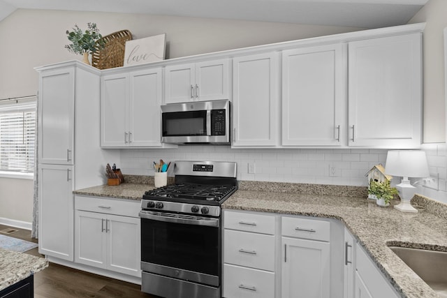 kitchen featuring appliances with stainless steel finishes, white cabinets, backsplash, and lofted ceiling