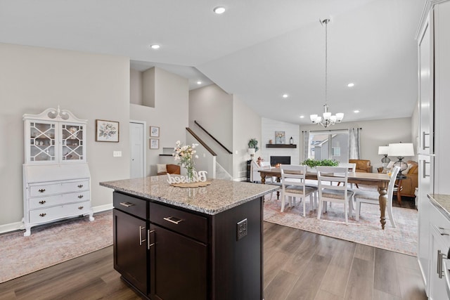 kitchen with dark wood-style flooring, lofted ceiling, open floor plan, a center island, and light stone counters