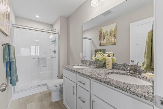 full bathroom featuring toilet, visible vents, a shower stall, and a sink