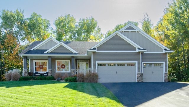 craftsman house featuring a front yard, an attached garage, stone siding, and aphalt driveway