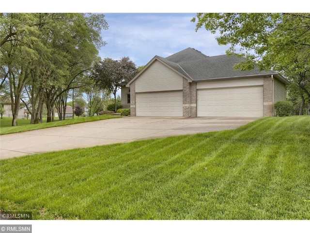 view of front of property featuring brick siding, a front lawn, an attached garage, and driveway