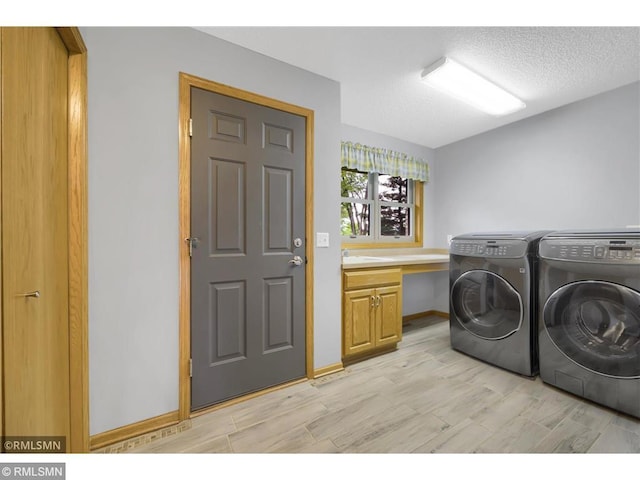clothes washing area featuring washer and dryer, cabinet space, light wood finished floors, a textured ceiling, and baseboards