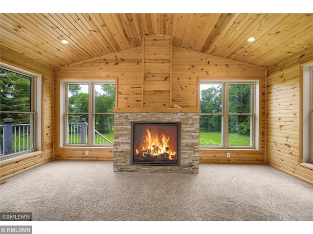 unfurnished living room featuring wooden walls, carpet floors, a fireplace, and lofted ceiling