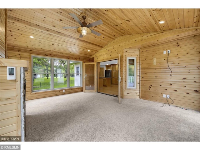 unfurnished living room with wooden walls, wood ceiling, carpet floors, and lofted ceiling
