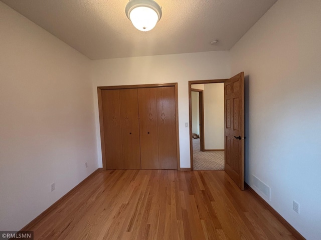unfurnished bedroom featuring baseboards, a closet, and light wood finished floors
