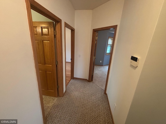 hall with baseboards and carpet flooring
