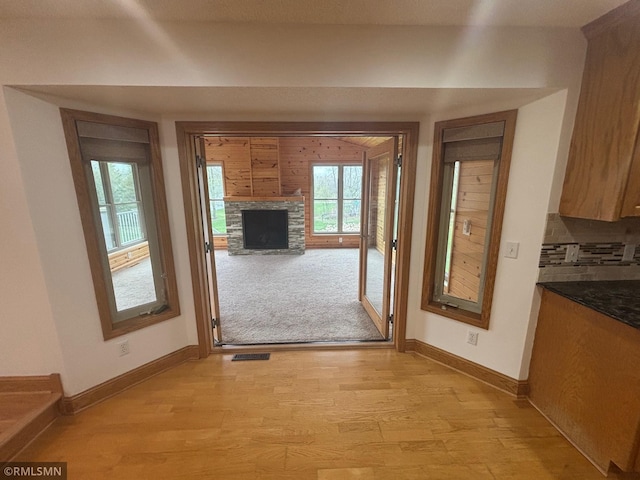 doorway featuring light wood-type flooring, baseboards, visible vents, and a fireplace