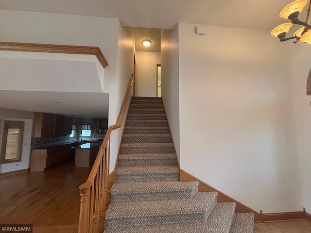 stairway with a notable chandelier and wood finished floors