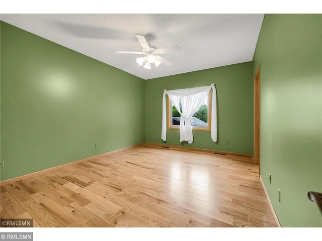 empty room with baseboards, a ceiling fan, and wood finished floors