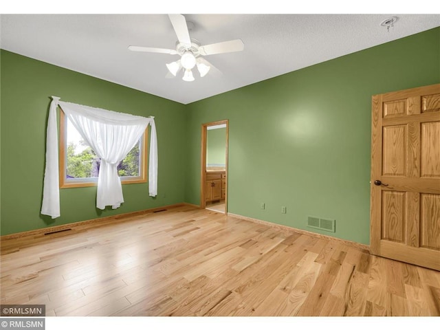 spare room featuring baseboards, a ceiling fan, wood finished floors, and visible vents