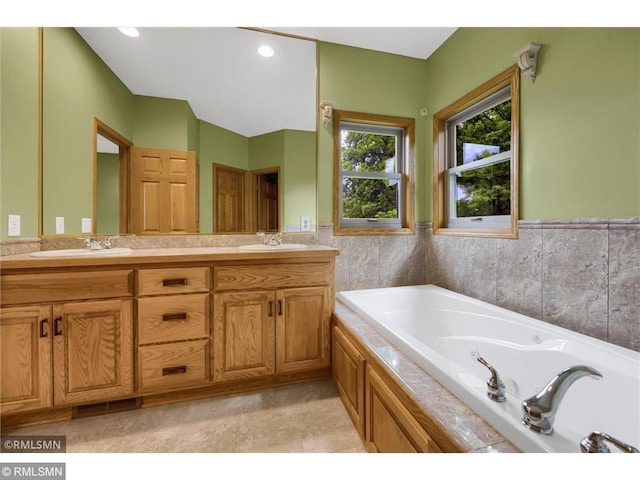 bathroom with double vanity, visible vents, a sink, and a garden tub