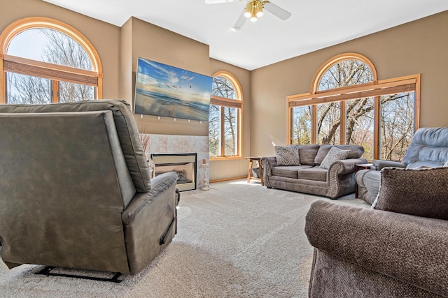 carpeted living area with ceiling fan, a tile fireplace, and a wealth of natural light