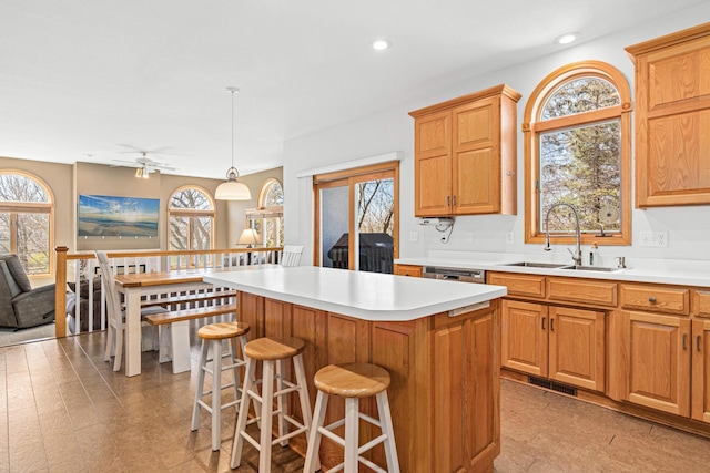 kitchen with a sink, a kitchen island, a breakfast bar, and light countertops