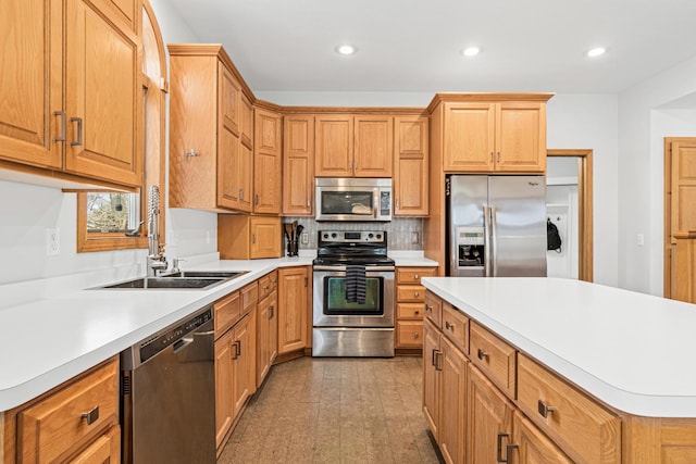kitchen with decorative backsplash, appliances with stainless steel finishes, a sink, light countertops, and recessed lighting