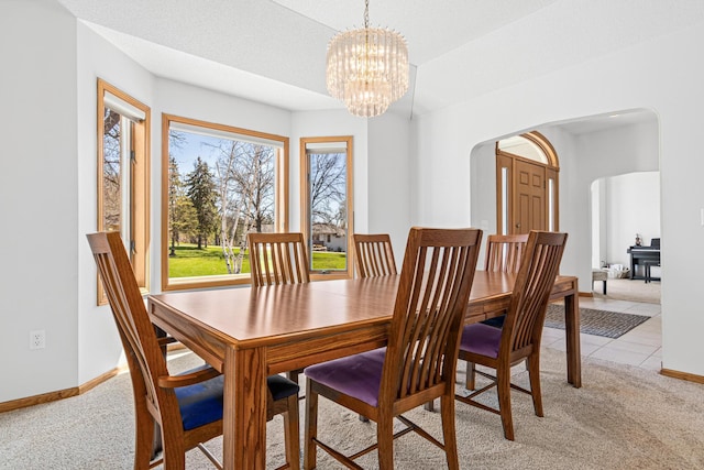 dining space featuring light colored carpet, arched walkways, baseboards, and an inviting chandelier