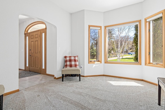 carpeted foyer entrance with baseboards and arched walkways