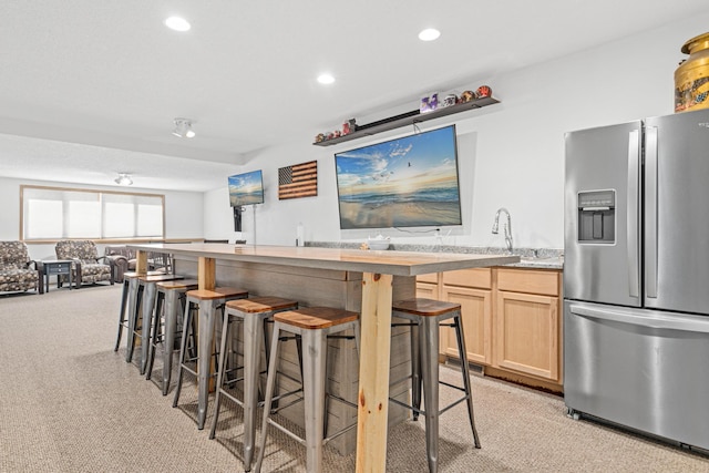 kitchen with a kitchen breakfast bar, light colored carpet, recessed lighting, and stainless steel fridge with ice dispenser