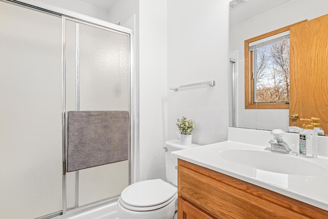 full bathroom with vanity, a shower stall, toilet, and visible vents