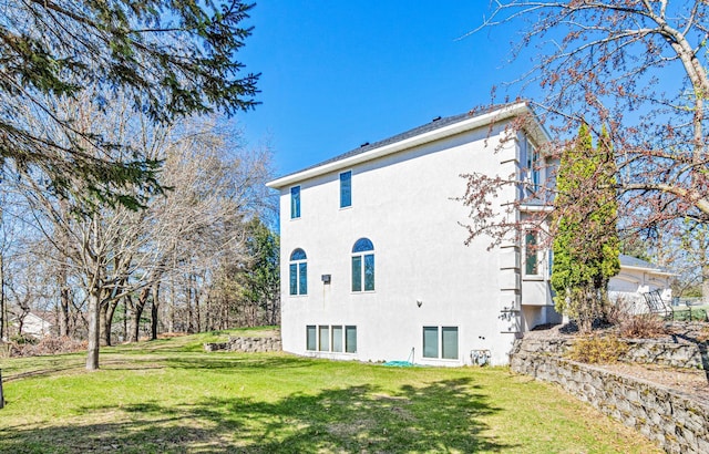 back of property with stucco siding and a yard