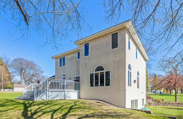 back of property with a lawn, stucco siding, and a deck