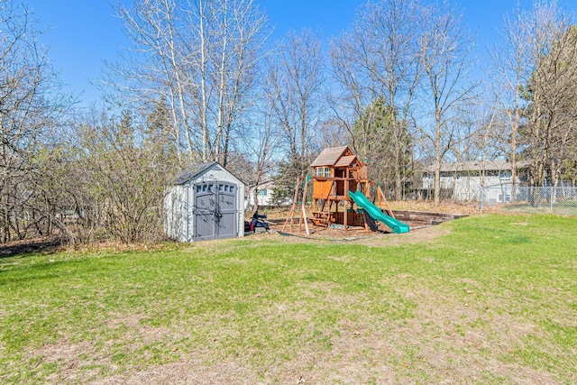 view of yard featuring a playground, a storage unit, an outbuilding, and fence